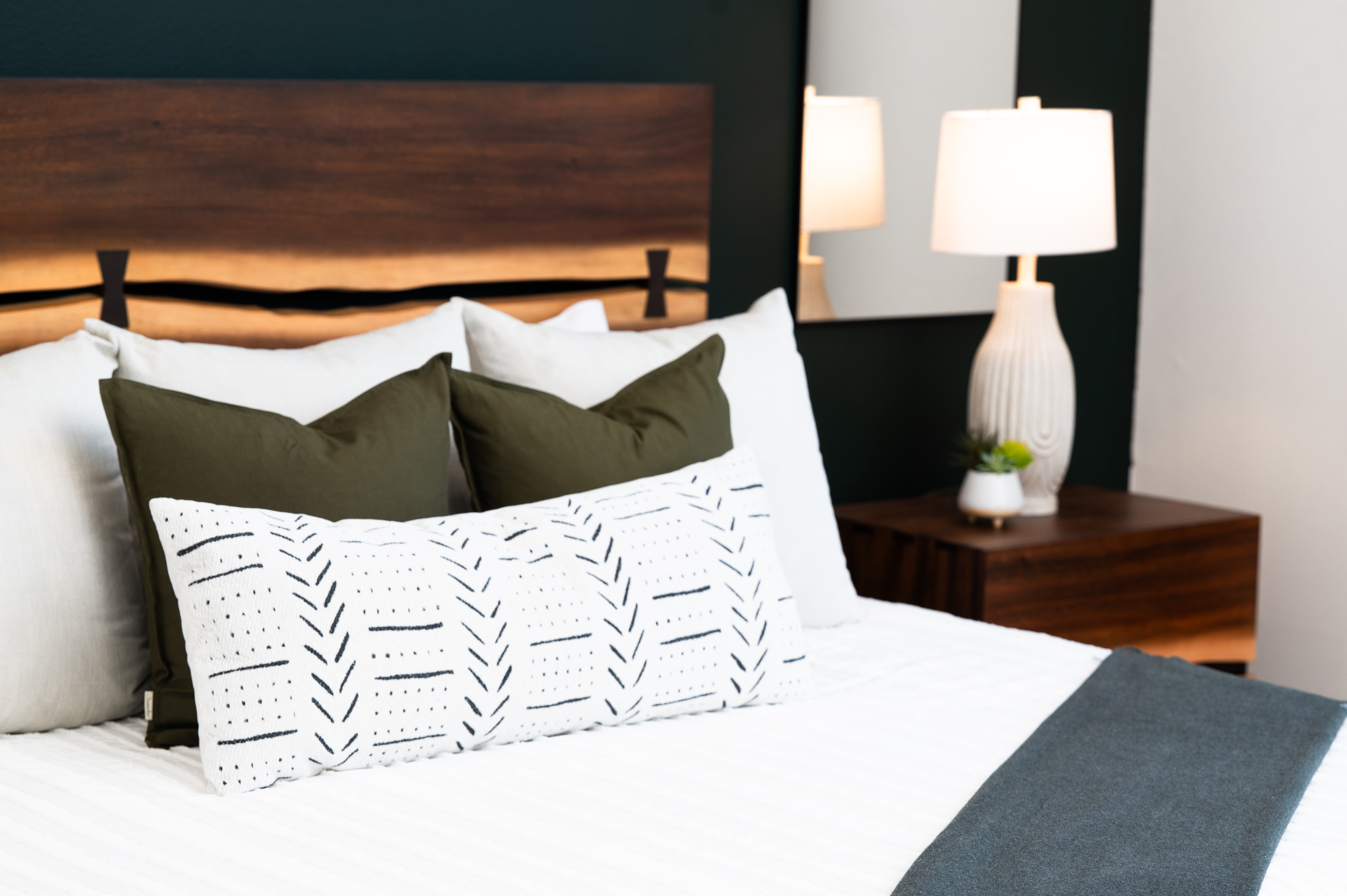 Designer primary bedroom with walnut headboard and hotel-style bedding