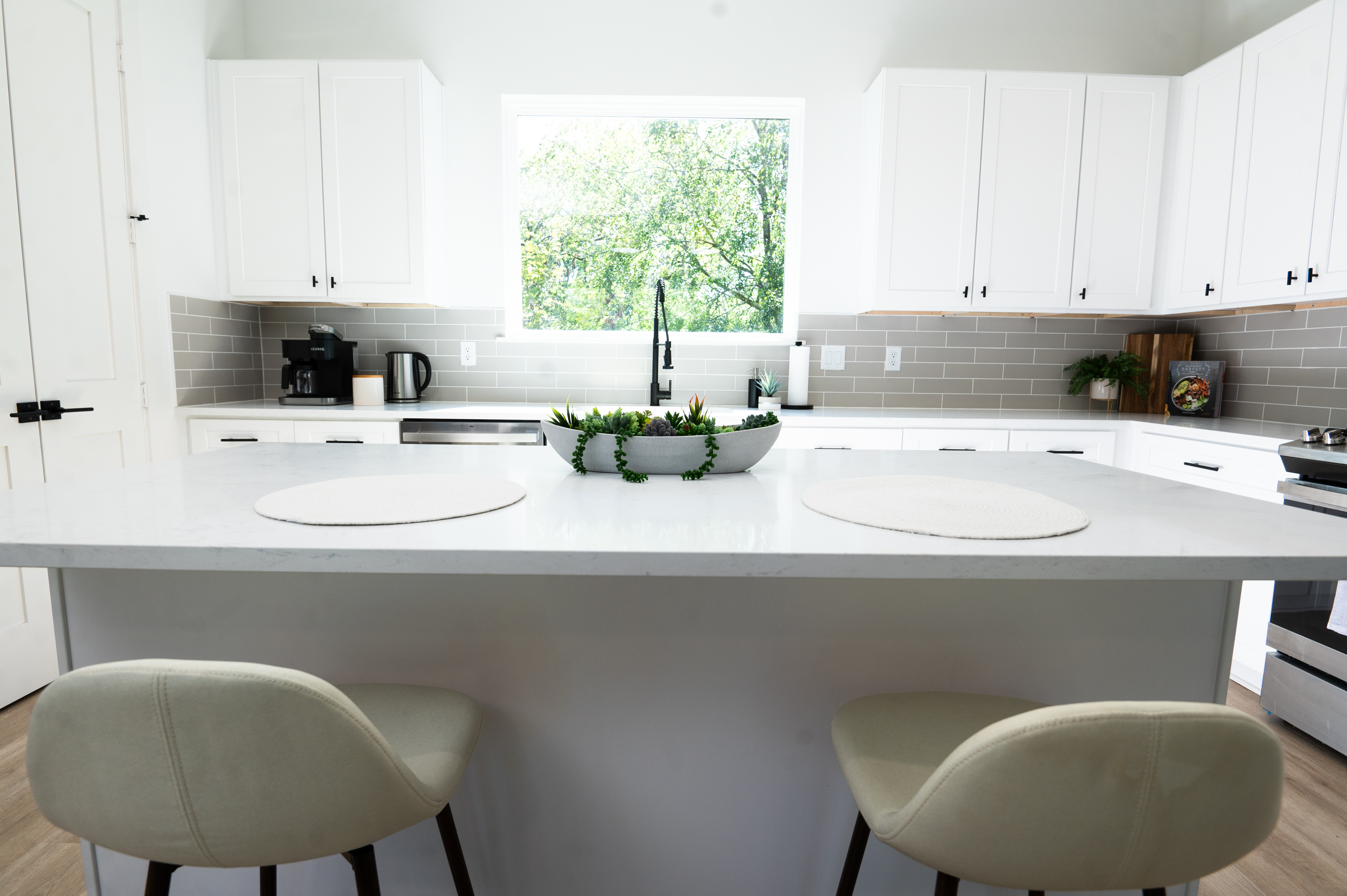 Chef's kitchen with quartz island, grey tile backsplash and garden window