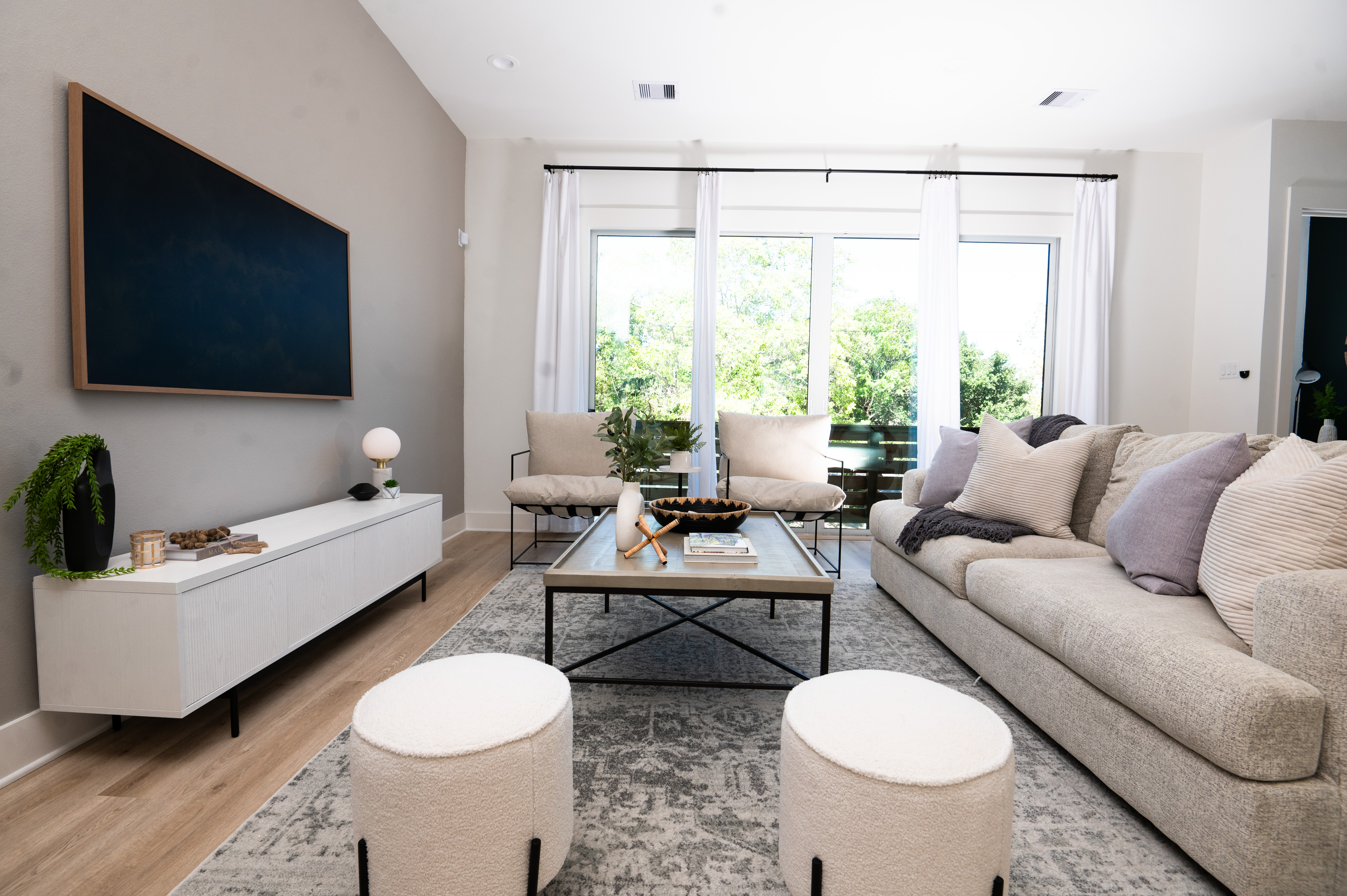 Bright, designer-furnished living room with vaulted ceilings and floor-to-ceiling windows